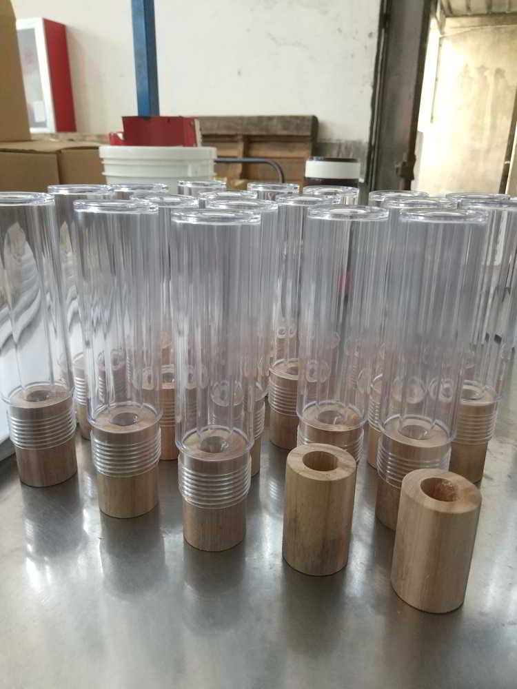 Batch of transparent injection molded tubes with wooden caps in a factory