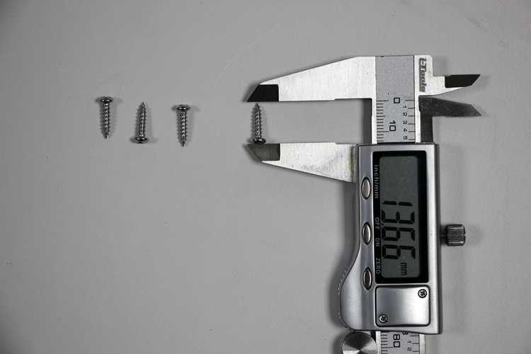 Digital caliper measuring small screws during a quality inspection
